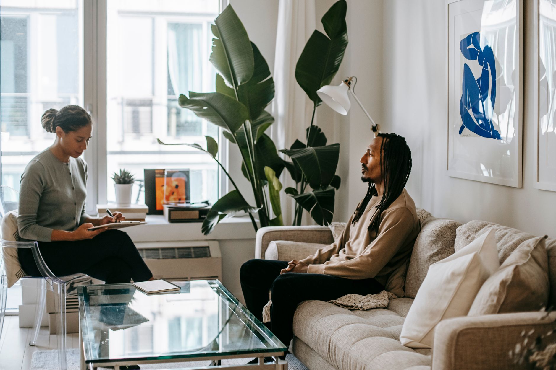 black woman writing on paper while talking to boyfriend indoors